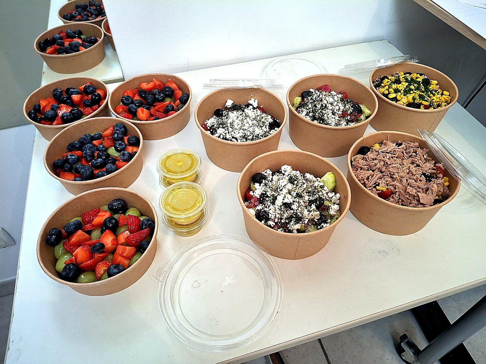 Bols kraft de salades fraîches SAINPLEMENT : salade grecque à la feta, salade de pâtes au thon et salades de fruits frais, avec leurs pots de vinaigrette maison